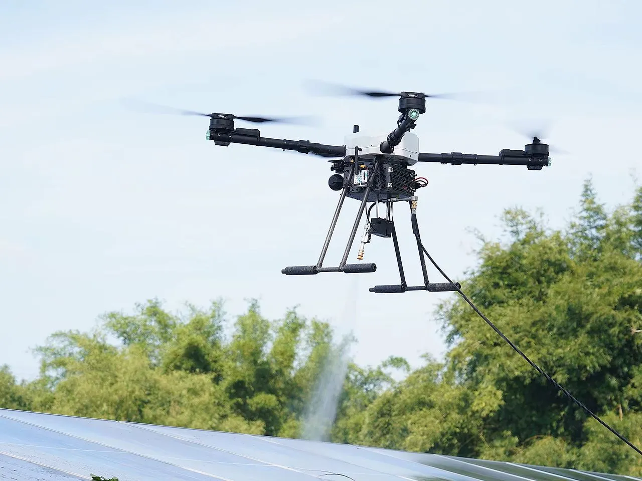 A drone washing rows of solar panels